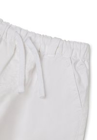 Shorts blancs avec une taille élastique et des cordons de serrage. Dotés de poches latérales et d'un petit logo brodé sur le devant. Texture lisse.