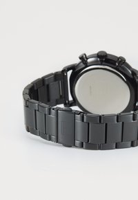 Montre chronographe noire avec un bracelet en acier inoxydable. Dispose d'un boîtier rond, de boutons-poussoirs texturés et d'un fond lisse et poli.