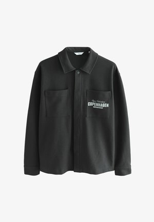 Veste en polaire noire avec un col évasé, deux poches avant et le texte imprimé "COPENHAGUE" sur la poche gauche.