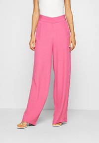 Pantalons larges rose avec une taille haute, fabriqués à partir d'un tissu lisse et léger. Présente une coupe propre, ajustée et droite.