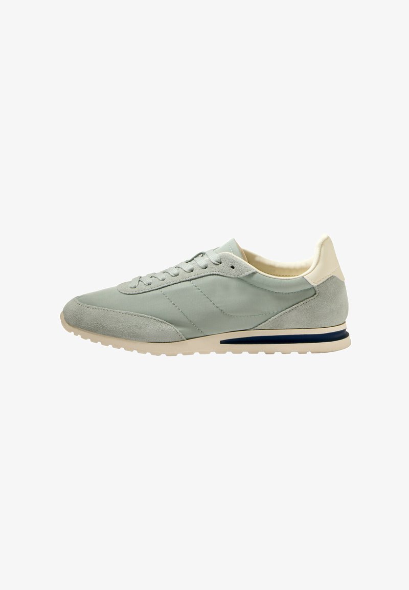 Light green sneakers featuring a mix of smooth and suede textures, rounded toe, lace-up design, and a contrasting navy blue accent on the sole.