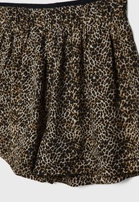 Sukně s leopardím potiskem, která se vyznačuje černobroušeným vzorem, skládáním a elastickým pasem pro pohodlné nošení a flexibilitu.