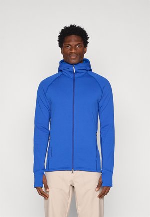 Veste zippée bleue avec capuche, fabriquée en tissu lisse et extensible. Comprend des passe-pouces, des poches latérales et un design ajusté.