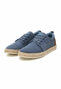 Zapatillas de lona azul con punteras redondas, suelas de yute trenzadas y detalles de cuero en los talones. Cuenta con cordones delanteros y un forro interior suave.