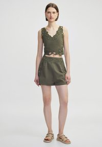Top corto de color verde oliva con ribete de encaje en forma de scallop y detalle de corte, combinado con pantalones cortos de tiro alto con bordado floral.