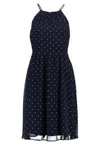 Robe bleu marine sans manches à pois blancs, fines bretelles, taille cintrée et jupe fluide se terminant au-dessus du genou.