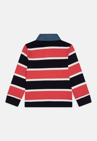 Rød, marineblå og hvit stripete langermet polo skjorte med denimkrage. Har en rett kant og ribbestrikkede mansjetter. Laget av myk bomull.