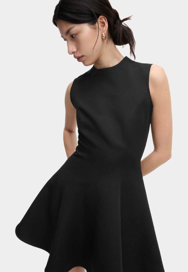 Schwarzes ärmelloses Kleid im ausgestellten Design, aus glattem Stoff mit sichtbaren Nähten, mit hohem Ausschnitt und enganliegender Oberteil.