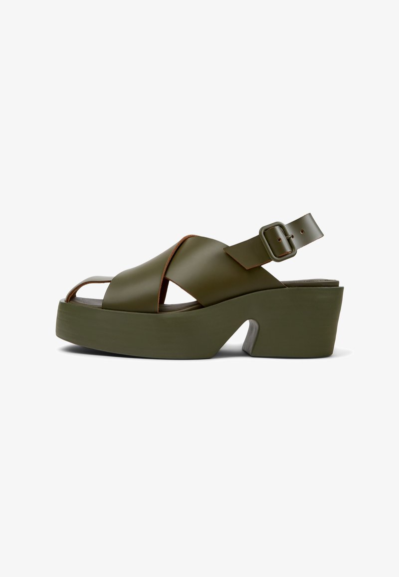 Green platform sandals with a wide cross-strap design, adjustable ankle buckle, and a chunky heel. Smooth material with a matte finish.