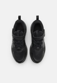 Chaussures de sport noires avec un dessus en maille, semelle en caoutchouc texturé, à lacets et fermeture velcro, avec un accent de logo sur le côté.