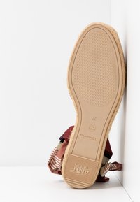 Braune Espadrille mit einer gewebten Jutesohle, gemustertem Stoff in Kastanienrot und Streifen, mit flachem Absatz und gummierter Außensohle für besseren Halt.