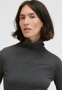 Gray turtleneck top made of a smooth, soft fabric. Fitted design with a high collar, minimalistic style, and no visible patterns or accents.