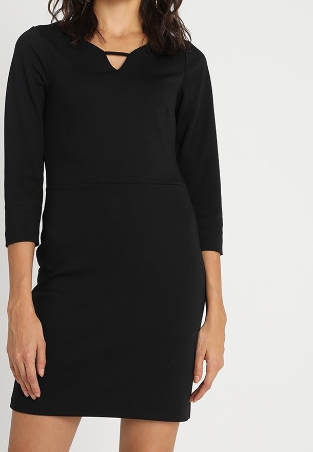 Robe noire ajustée avec manches trois-quarts, un décolleté en U avec une petite ouverture en forme de goutte, et une texture lisse et extensible.