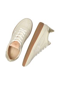 Sneakers crema con tomaia in pelle liscia, dettagli in camoscio, lacci bianchi e suola in gomma marrone. Presentano un sottile dettaglio con logo.