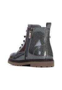 Botín negro brillante de tobillo con cremallera lateral, punta redonda, parte delantera con cordones, superficie texturizada y suela gruesa de goma con una banda de rodadura marrón.