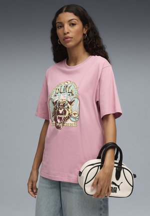 Pink cotton t-shirt with a graphic of a roaring leopard and "PUMA" text, paired with a small white handbag featuring black accents and logo.