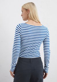 T-shirt à manches longues présentant des rayures horizontales bleues et blanches, un col rond et une coupe ajustée. Matière en coton avec une texture lisse.