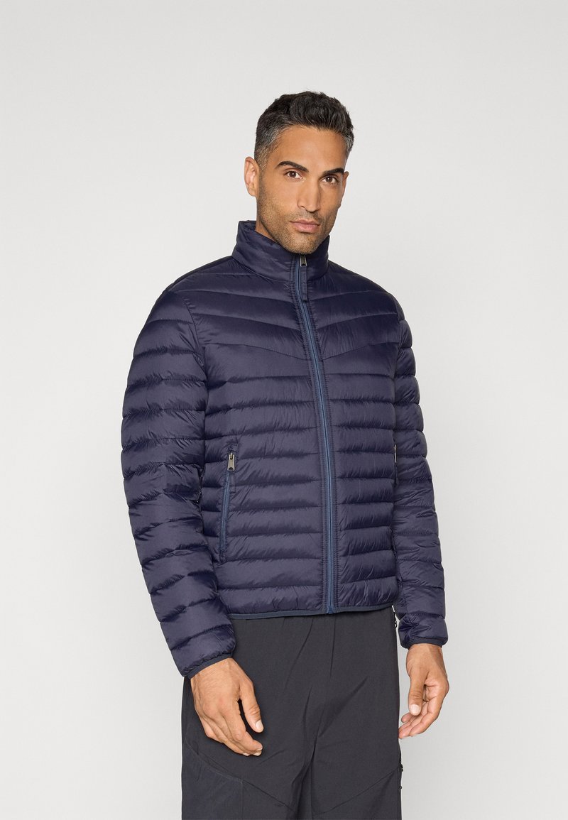 Marineblaue Steppjacke mit hohem Kragen, horizontalem Steppmuster, durchgehendem Reißverschluss und seitlichen Taschen mit dezenten Akzenten.