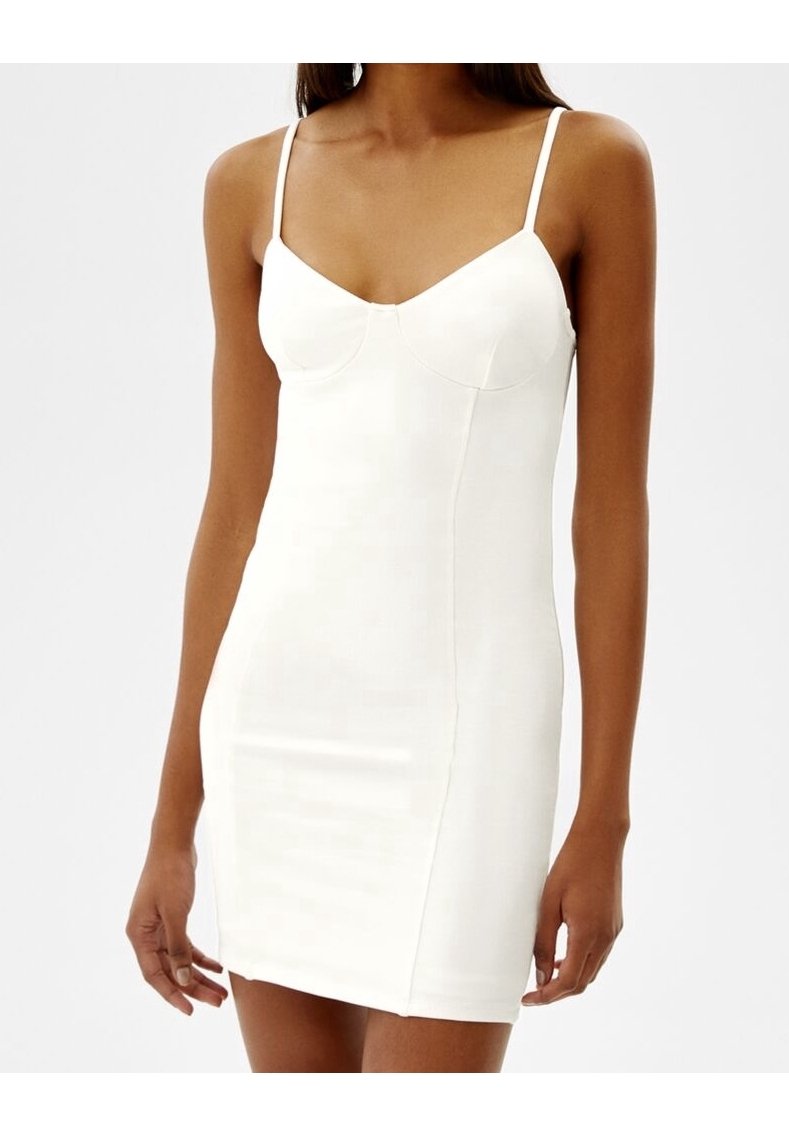 Robe blanche ajustée avec de fines bretelles spaghetti, un décolleté en cœur et une texture lisse et extensible. Longueur au-dessus du genou.