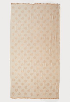 Couverture tissée beige présentant un motif circulaire répétitif. Les bords sont ornés de franges légères. Le matériau semble doux et texturé.