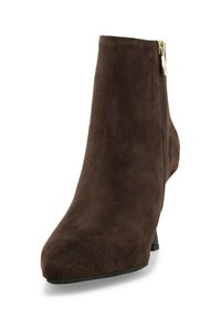 Stivaletto alla caviglia in suede marrone con tacco basso e cerniera laterale. Texture liscia e design con punta appuntita. Dettaglio di cuciture sobrie lungo le cuciture.