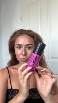 Bouteille de spray rose étiquetée "Maybelline Lasting Fix" avec un capuchon noir. La bouteille présente un texte noir en gras et une finition mate.