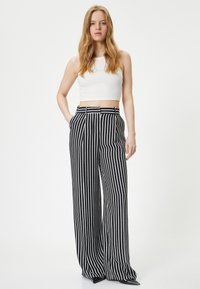 Wijde, hoge taille zwarte en witte gestreepte broek van geweven stof, met plooien en een aansluitende tailleband.
