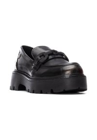 Zapato de cuero negro con suela gruesa y estriada y cordones trenzados. El diseño incluye una textura suave y una puntera redondeada con un ligero brillo.