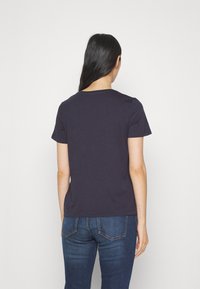 Granatowa koszulka z krótkim rękawem, wykonana z gładkiej bawełny, z okrągłym dekoltem i luźnym krojem, w połączeniu z ciemnoniebieskimi dżinsami.