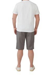 Witte T-shirt met korte mouwen, grijze korte broek en witte sneakers. T-shirt heeft een ronde hals; de korte broek is knielang en heeft een gladde textuur.