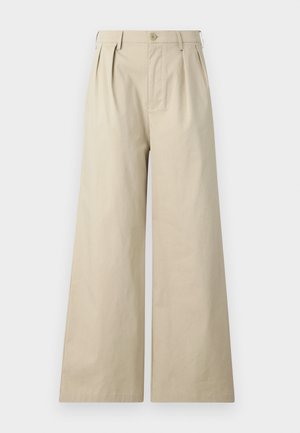 Smėlio spalvos plačios kelnės, pagamintos iš medvilnės, su klostėmis, mygtuko užsegimu ir šoniniais kišenėmis, su lygiu ir minkštu paviršiumi.