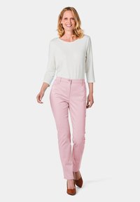 Lichte, langärmige witte top gecombineerd met nauwsluitende roze broek. De outfit heeft een gladde textuur en een klassiek ontwerp met een eenvoudige silhouet.