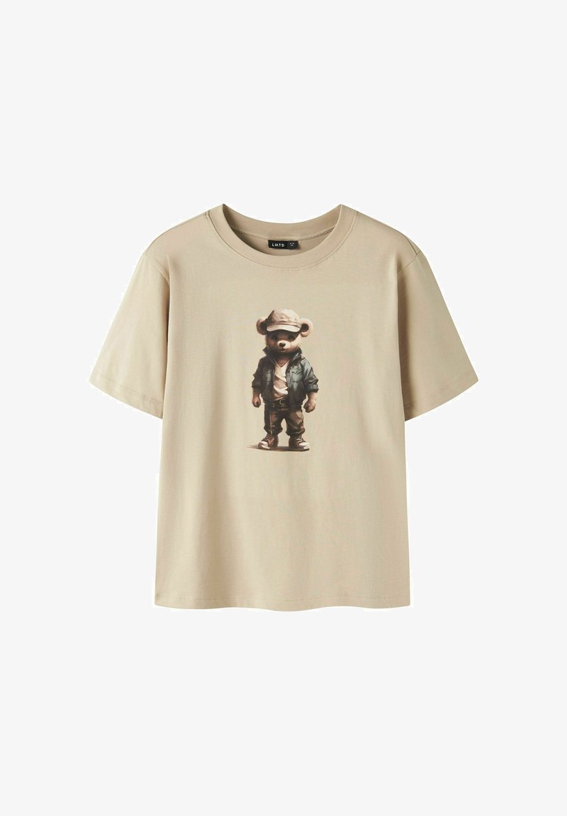 T-shirt beige à manches courtes avec un motif d'ourson portant une casquette, une veste, une chemise blanche, un pantalon et des chaussures, centré sur le devant.