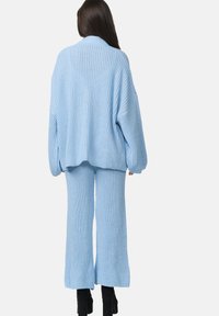 Ensemble en tricot bleu clair comprenant un pull et un pantalon à jambe large. Texture côtelée, coupe ample et manches longues avec un design à épaule déchue.