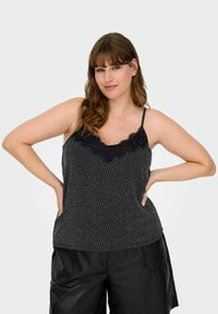 Camiseta de tirantes negra con estampado y encaje en el escote, con tirantes ajustables y un corte relajado, combinada con pantalones cortos negros de corte holgado.