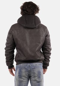 Giacca bomber in pelle marrone con cappuccio, polsini a coste e una texture liscia. Dettagli di cucitura distintivi lungo le spalle e la schiena.