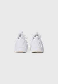 Chaussures de sport blanches avec un dessus texturé, un col rembourré et une semelle épaisse. Des lacets et des languettes à l'arrière sont également présents.