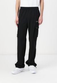 Zwarte cargobroek met een elastische tailleband, zijzakken en een ritszakdetail. Gemaakt van een zachte, lichte stof.