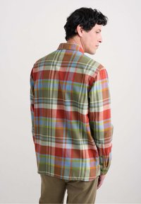 Overhemd met knopen in een ruitpatroon in de kleuren rood, groen, blauw en wit. Gemaakt van zachte stof met een kraag en lange mouwen.