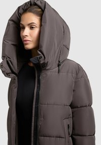 Brown puffer jacket with a large hood, zippered front, and two side pockets. The fabric has a smooth, shiny texture and appears insulated.