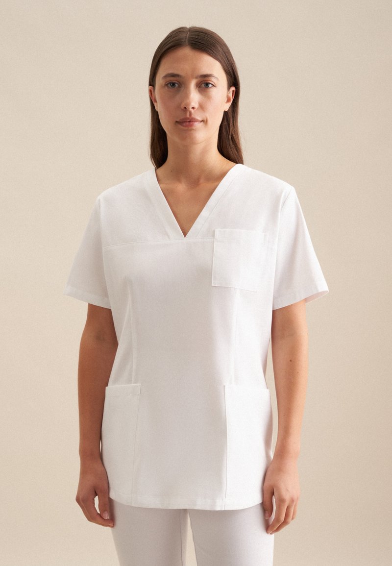 Maglia da lavoro bianca con scollatura a V, maniche corte, tasca sul petto e due tasche frontali. Realizzata in un tessuto liscio e leggero.