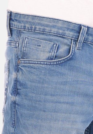 Jeans de denim azul claro con un diseño clásico de cinco bolsillos, corte slim y una sutil textura desgastada con un pequeño detalle en el bolsillo frontal.
