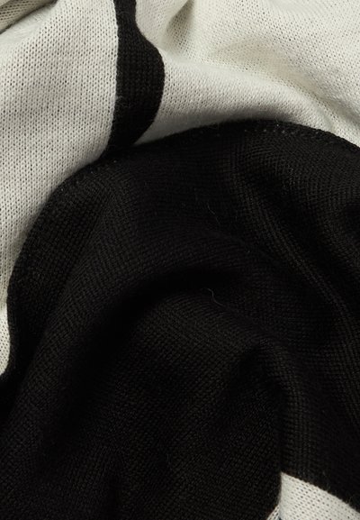 Gros plan sur un tissu tricoté doux avec des blocs de couleur noir et blanc montrant la texture et les plis.
