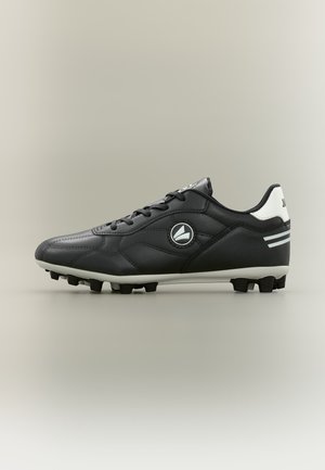 Chaussure de football noire et blanche à lacets, avec des crampons arrondis sous la semelle et un logo circulaire sur le côté, vue de l'extérieur.