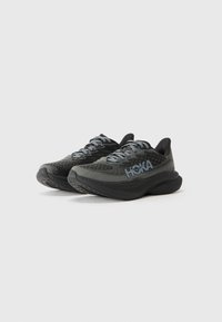 Baskets de course noires en maille respirante. Semelle en caoutchouc épaisse, design rembourré et lacets gris avec le logo HOKA affiché en évidence.