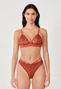 Kanten beha en bijpassende string in diep rood. De beha heeft een driehoekige vorm met decoratieve kant en banden. De string heeft vergelijkbare kantdetails.