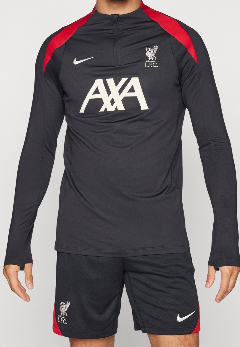 Schwarzes Langarm-Sportoberteil mit roten Akzenten, ausgestattet mit hohem Kragen und Reißverschluss, kombiniert mit schwarzen Shorts und weißem Nike-Logo sowie L.F.C.-Emblem.