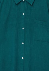 Chemise bleu sarcelle en tissu texturé, avec une fermeture boutonnée à l'avant, des boutons blancs, un col classique et une poche poitrine unique.