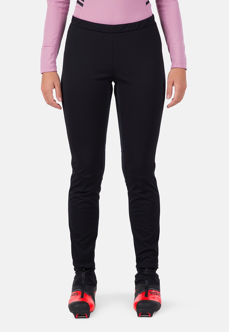 Zwarte sportbroek met een aansluitend ontwerp, gemaakt van rekbaar materiaal, met naden voor beweging, gecombineerd met rode en zwarte skibotten.