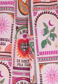 Un tissu multicolore présente un design fantaisiste avec des motifs de soleil, de cœur et de feuille en rose, vert et orange sur un fond clair.
